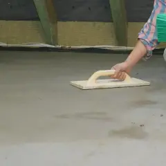 Pracownik wygładza świeży beton kielnią. Czas, po jakim zacierać beton, zależy od warunków.
