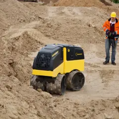 Na budowie pracuje operator z pilotem, sterując maszyną Bomag BMP 8500.