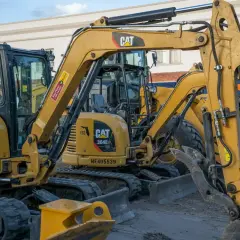 Żółte minikoparki CAT stoją obok siebie. Zastanawiasz się, ile wykopie minikoparką w godzinę?