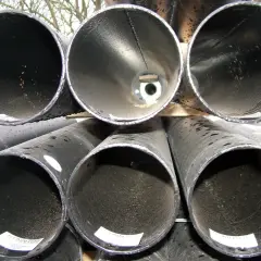 Stosy rur stalowych, gotowych do cięcia. Widać ich wnętrza, niektóre z widocznymi elementami technicznymi.