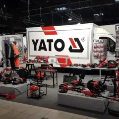 Stoisko targowe z narzędziami YATO. Widać ciężarówkę z logo, ekspozycje narzędzi ręcznych i elektronarzędzi. YATO to znana firma z branży narzędziowej.