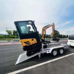 Mini koparka Sany SY18C na przyczepie, gotowa do transportu. Obok biały bus i inne przyczepy.