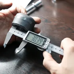 Precyzyjne pomiary: jak mierzyć mikrometrem. Dłoń trzymająca metalowy element i cyfrowy suwmiarkę, która pokazuje 30.39 mm.