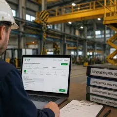 Pracownik w hali przemysłowej wypełnia wniosek online o przedłużenie uprawnień UDT. Obok stos dokumentów: "Uprawnienia UDT", "Świadectwa kwalifikacji".