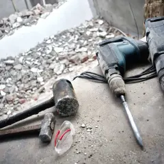 Dwa młoty udarowe i młotki leżą na gruzach. Przygotowania do wiercenia w betonie.
