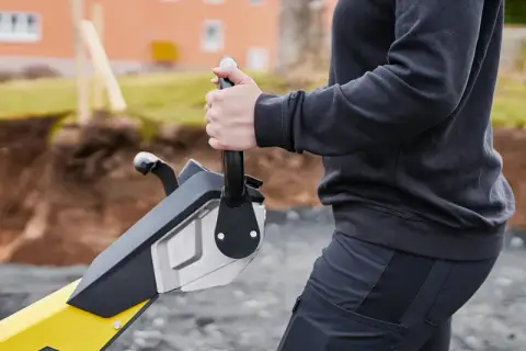 Operator steruje zagęszczarką z rewersem. Maszyna jest gotowa do pracy na budowie.