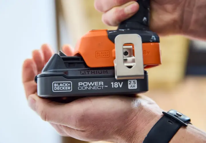 Dłoń trzyma akumulator 18V 2.5Ah do elektronarzędzi Black+Decker. To solidny sprzęt stolarski.