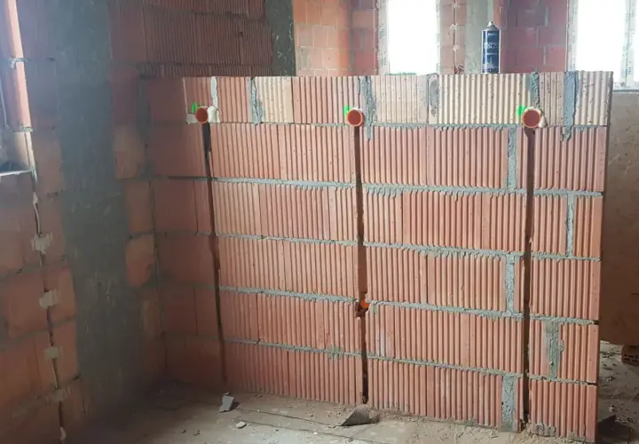 Wykonano bruzdy pod kable w ścianie z pustaków ceramicznych. Widoczne są puszki instalacyjne.