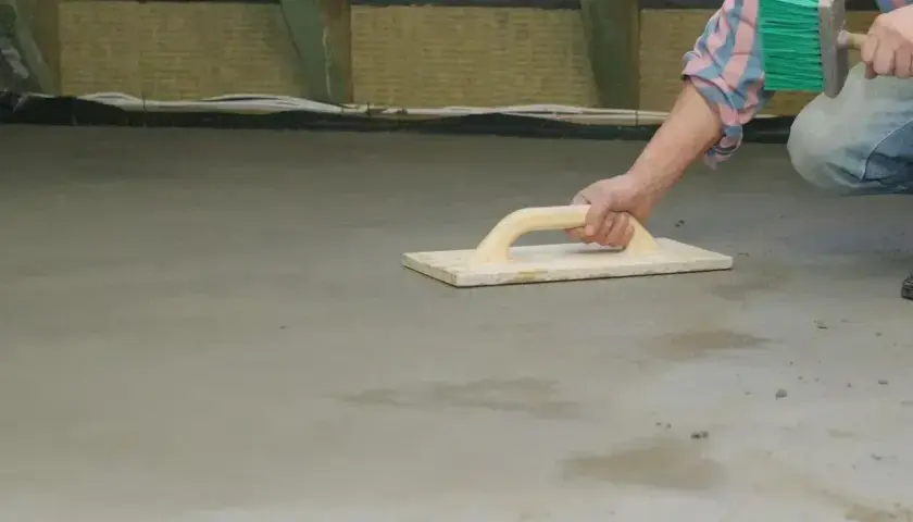 Pracownik wygładza świeży beton kielnią. Czas, po jakim zacierać beton, zależy od warunków.