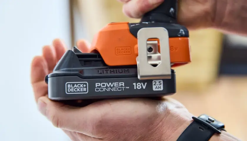 Dłoń trzyma akumulator 18V 2.5Ah do elektronarzędzi Black+Decker. To solidny sprzęt stolarski.