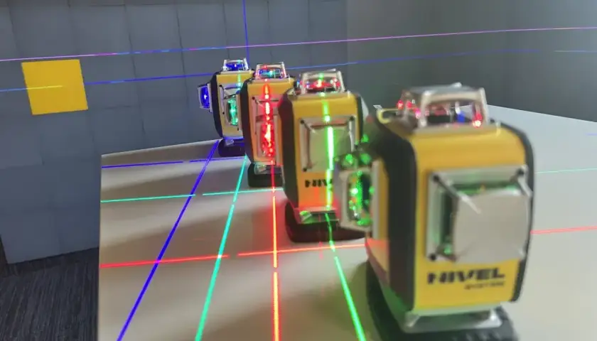 Linie laserowe w kolorach czerwonym, zielonym i niebieskim tworzą siatkę na stole. Kilka żółtych poziomnic laserowych emituje ten widoczny w dzień laser.