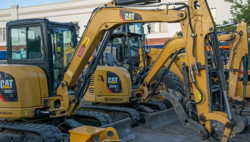 Żółte minikoparki CAT stoją obok siebie. Zastanawiasz się, ile wykopie minikoparką w godzinę?