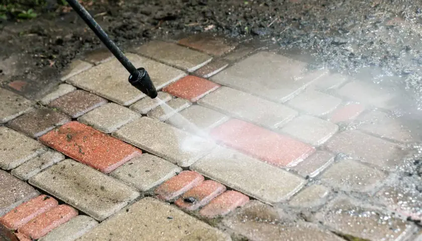 Myjka ciśnieniowa czyści ścieżkę z kostki brukowej, przywracając jej dawny blask. Zagęszczanie kostki to ważny etap prac.
