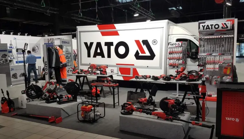 Stoisko targowe z narzędziami YATO. Widać ciężarówkę z logo, ekspozycje narzędzi ręcznych i elektronarzędzi. YATO to znana firma z branży narzędziowej.