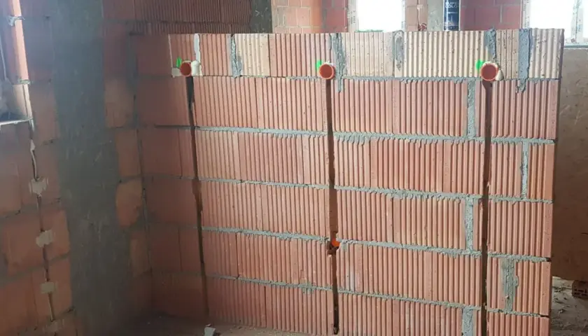 Wykonano bruzdy pod kable w ścianie z pustaków ceramicznych. Widoczne są puszki instalacyjne.