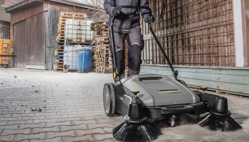 Osoba używa profesjonalnej zamiatarki do kostki brukowej Karcher, by szybko i skutecznie posprzątać teren.