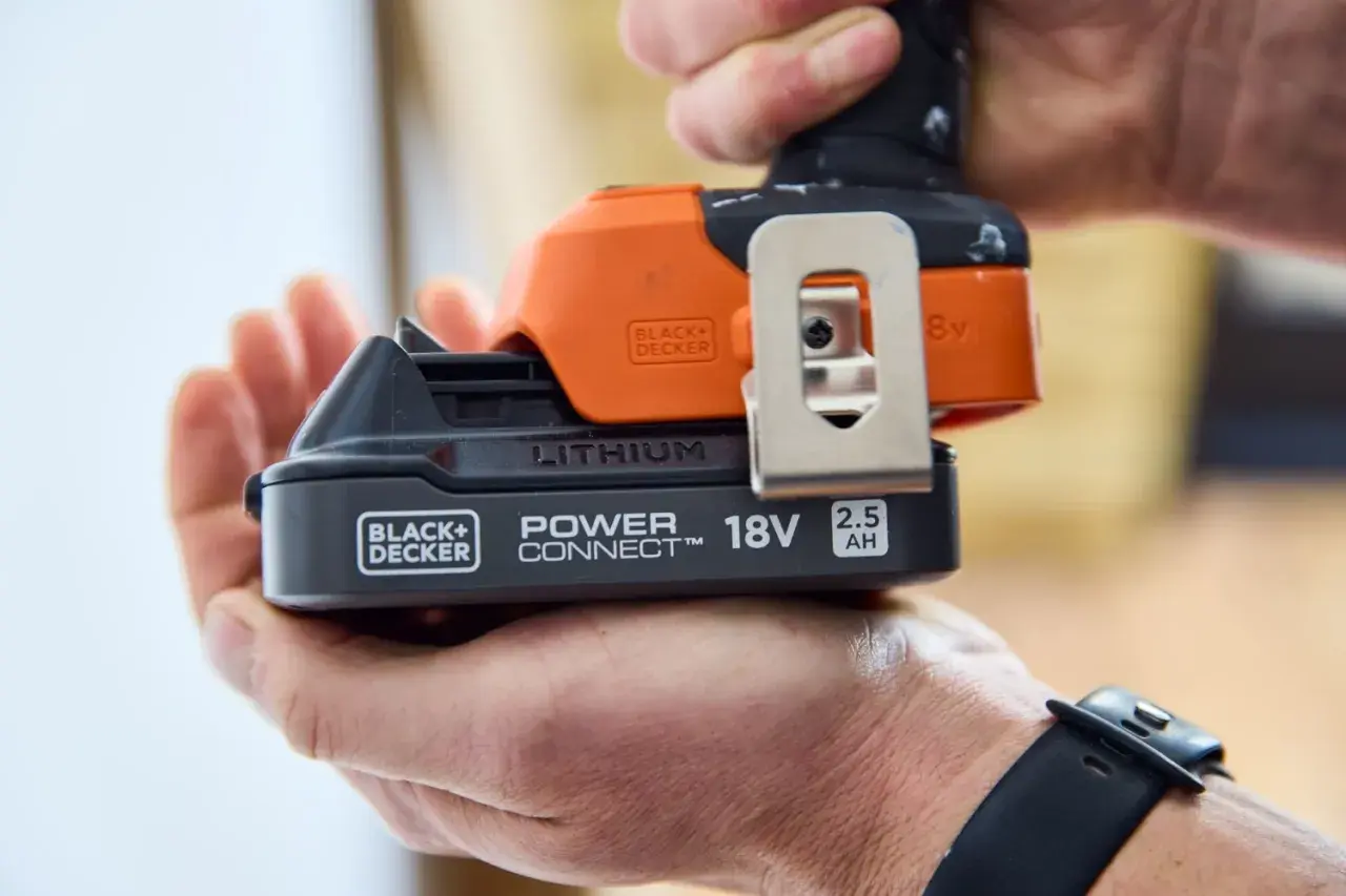 Dłoń trzyma akumulator 18V 2.5Ah do elektronarzędzi Black+Decker. To solidny sprzęt stolarski.