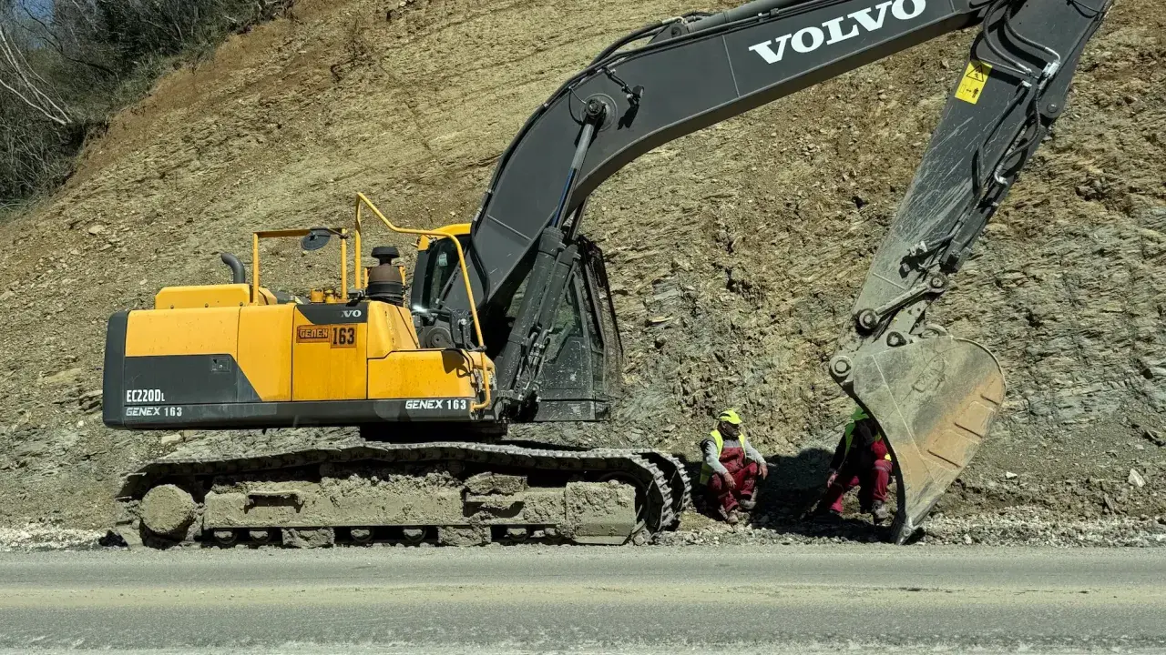 Żółta koparka Volvo EC220D z numerem GENEX 163 pracuje przy osuwisku. To jeden z wielu rodzajów koparek budowlanych.