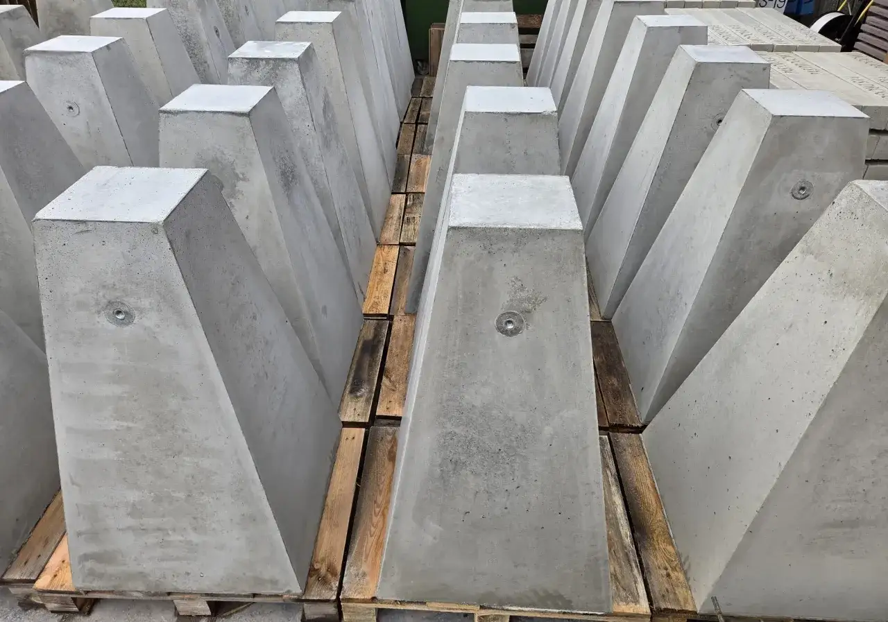 Rzędy betonowych słupków, które mogą służyć jako oznaczenia geodezyjne w terenie. Każdy słupek ma metalowy element na górze.