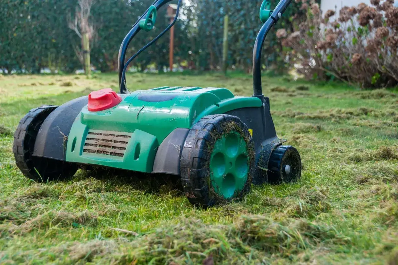 Zielony aerator na trawniku. Zastanawiasz się, aerator co to? To urządzenie do napowietrzania gleby, kt&oacute;re poprawia jej strukturę i zdrowie trawy.