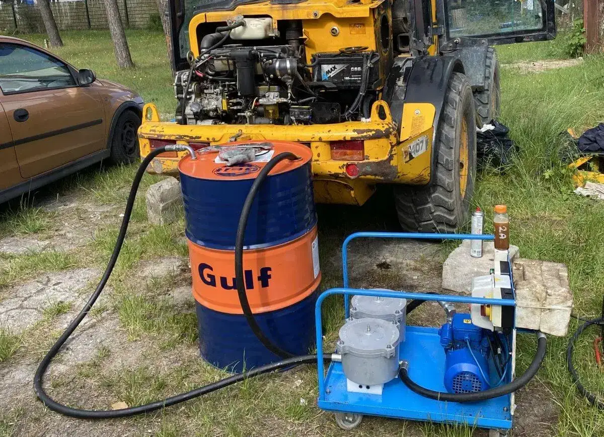 Pompa i beczka Gulf do uzupełniania oleju hydraulicznego w koparce. Sprawdzanie poziomu oleju jest kluczowe.